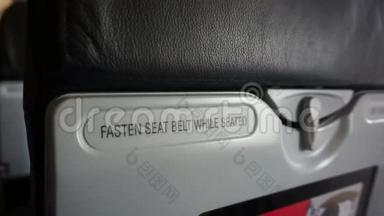视频紧固安全带，而坐和救生衣下面的座位标志跨越飞机座位。 摘要安全
